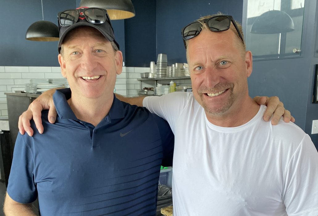 2 men standing next to each other smiling